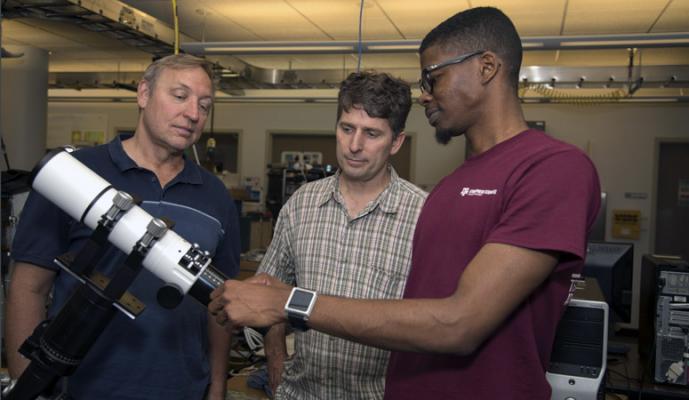 Intern and mentors examine a telescope