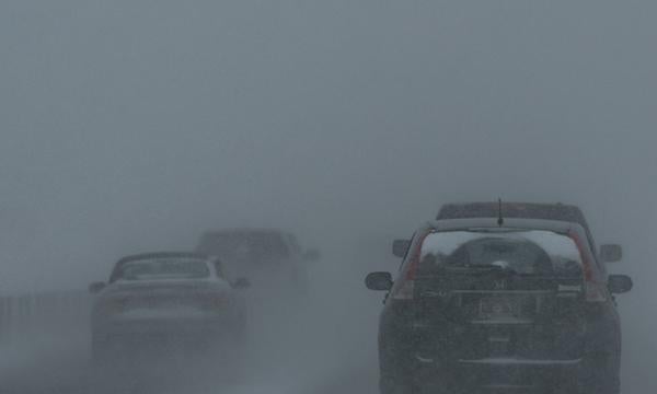 Vehicles travel through fog on winter road